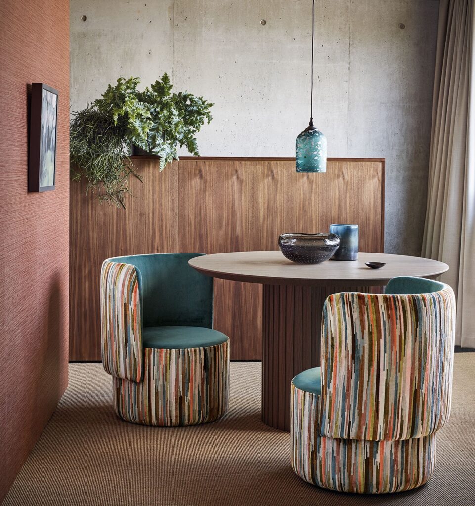 Colorful dining chairs sit at a short brown table.