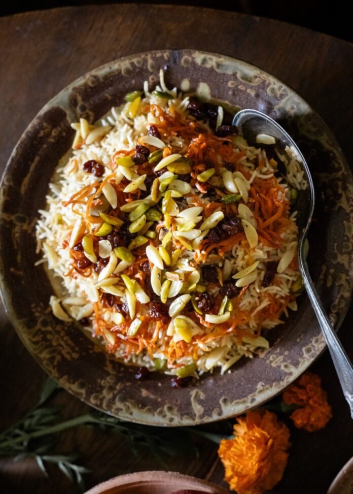 A black bowl full of Afghani Kabuli Pulao (Rice Pilaf) with nuts over top.