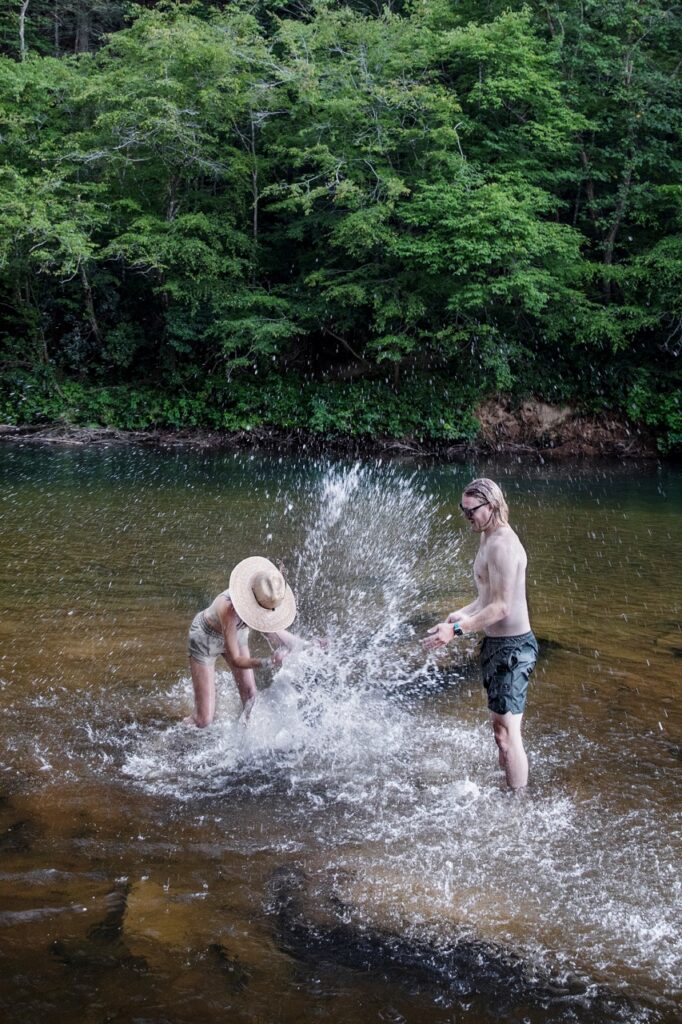 A man and woman splash each other in a river.