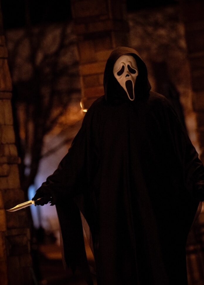 Ghost face from Scream 7 walks with a knife out at his side.
