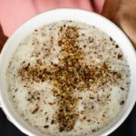 A white bowl of Sheer Birinj Afghan rice pudding with crushed walnuts forming a cross.