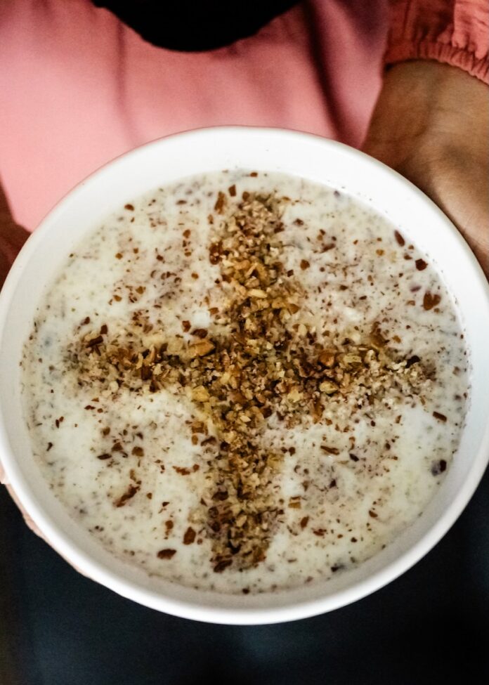 A white bowl of Sheer Birinj Afghan rice pudding with crushed walnuts forming a cross.