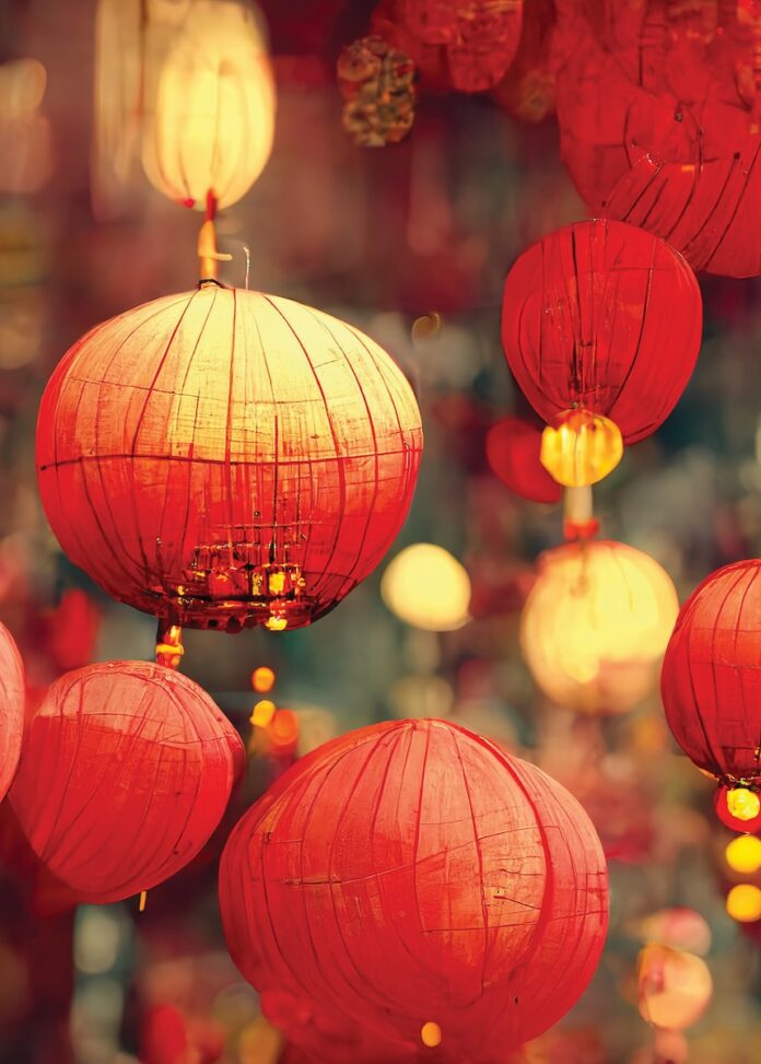 Paper lanterns in a red color for the New Year in China hang from the ceiling with lights inside of them.