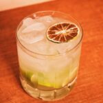 A short glass with lime wedges at the bottom, a lot of ice, and a dried lime wheel on top.