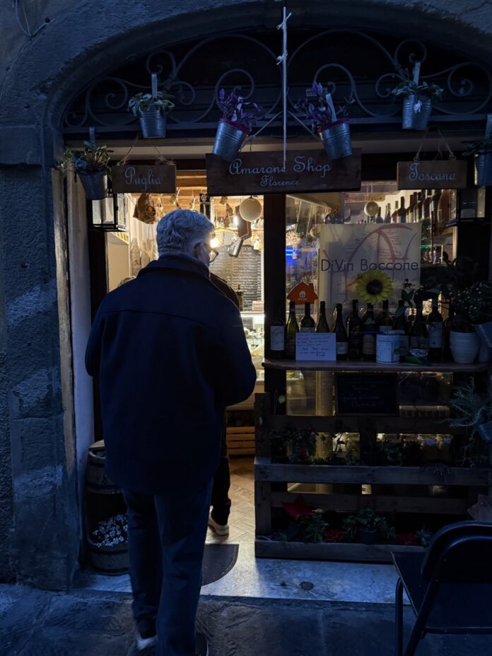 A man in a jacket walks into a small shop front.