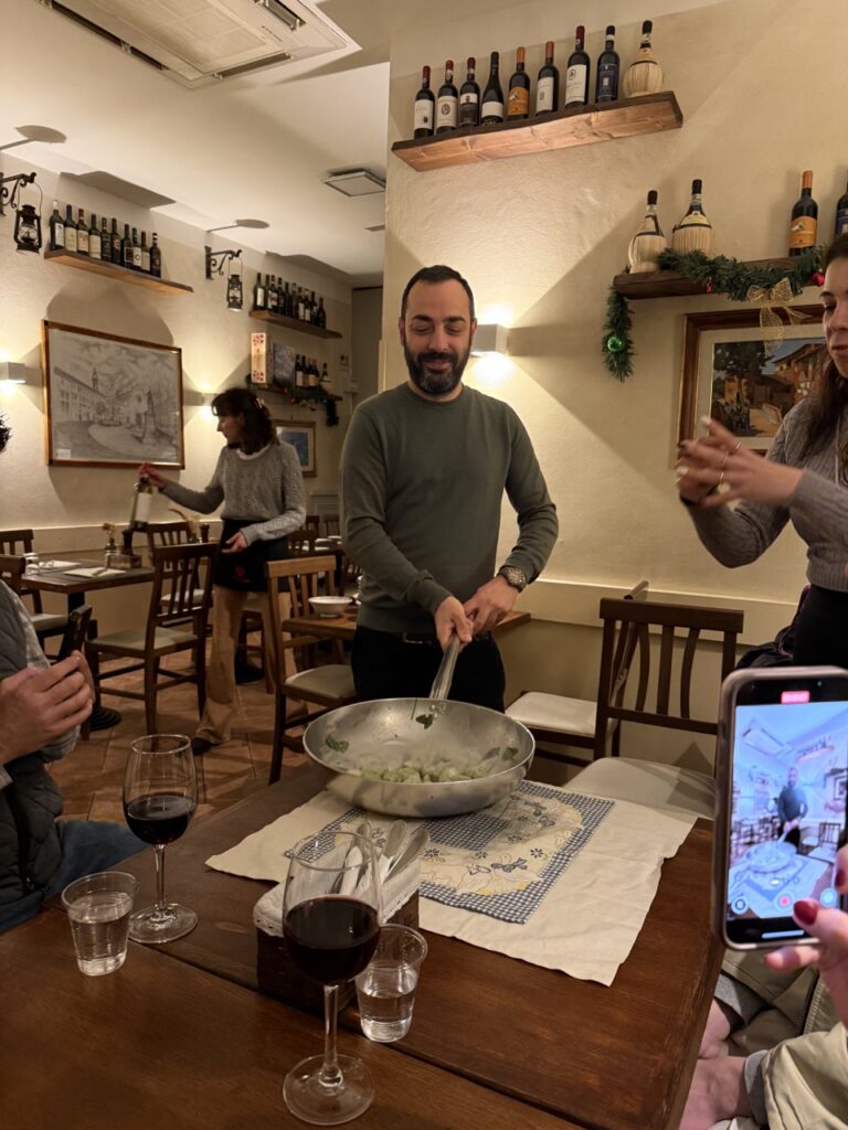 A man cooks pasta in a pan at the dinner table.