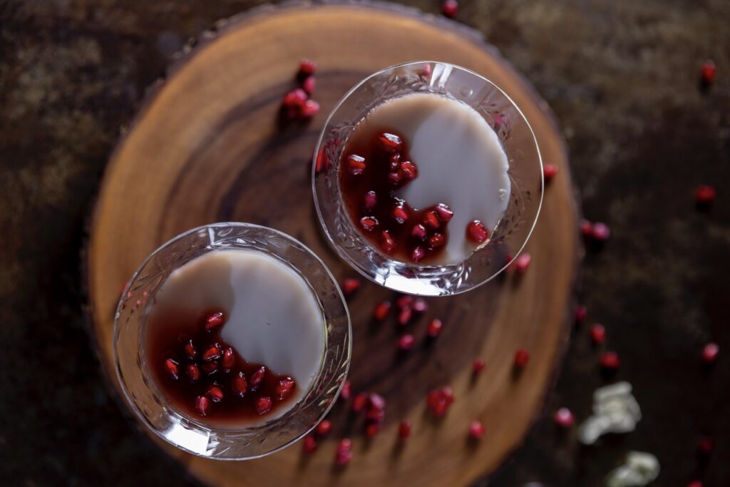 Two glasses of white pudding, manjar blanco, with pomegranate seeds everywhere.