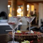 Three cups full of a white pudding with red pomegranate seeds on top.