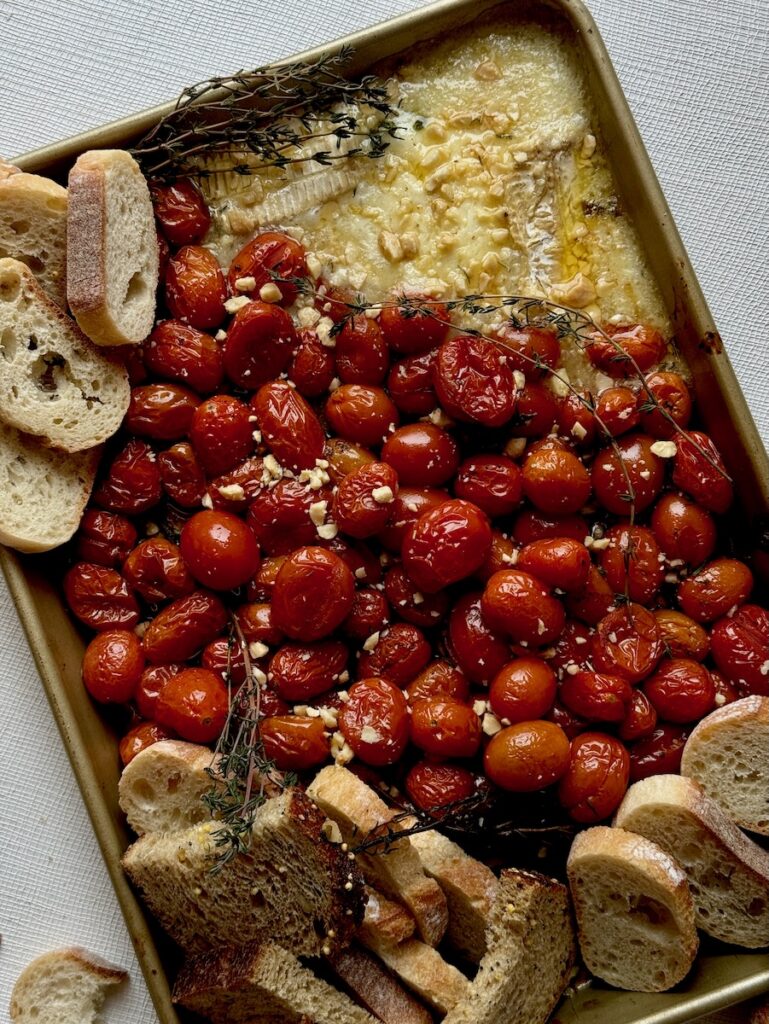 A tray full of tomatoes and feta with small pieces of bread surrounding it. 