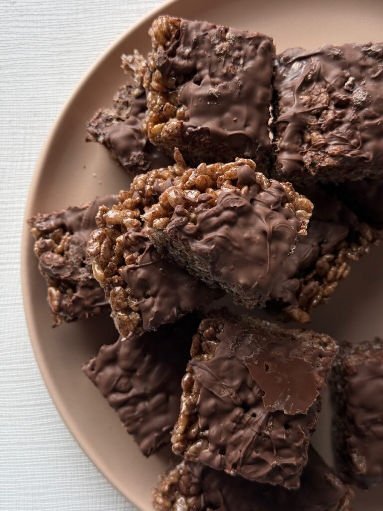 Chocolate covered rice krispy treats on a brown plate.
