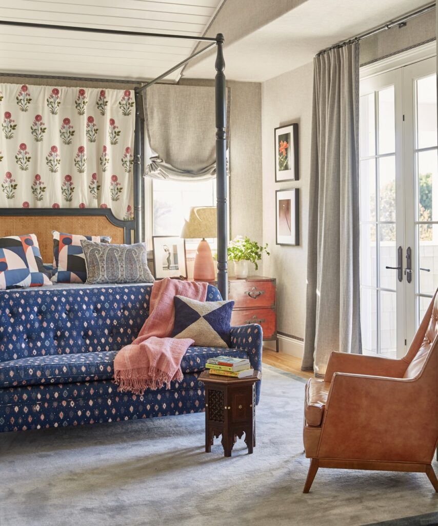 A balcony doorway in a bedroom with a blue couch at the end of the bed.