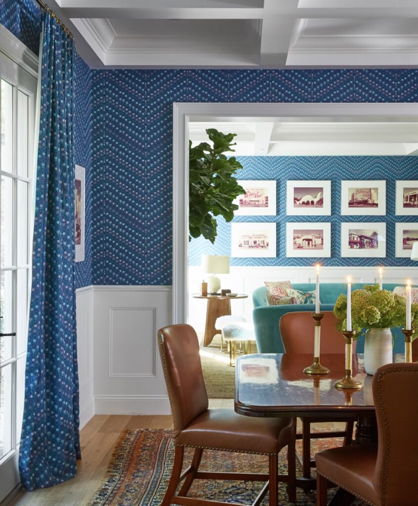 A blue walled sining room with a dark table and brown leather chairs.