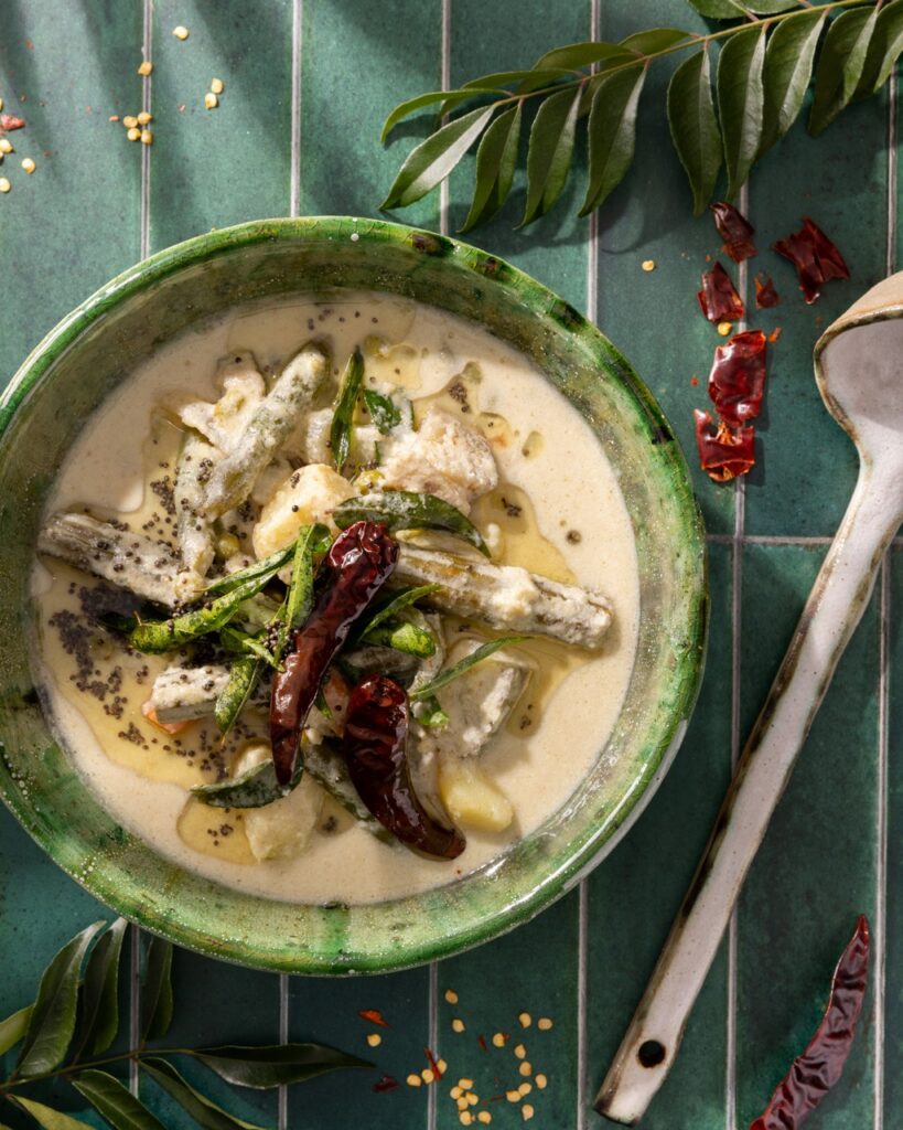 A green bowl with creamy coconut soup and veggies inside it.