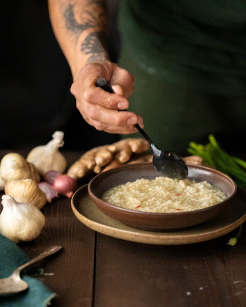 A person spreads out porridge in a bowl using a spoon.