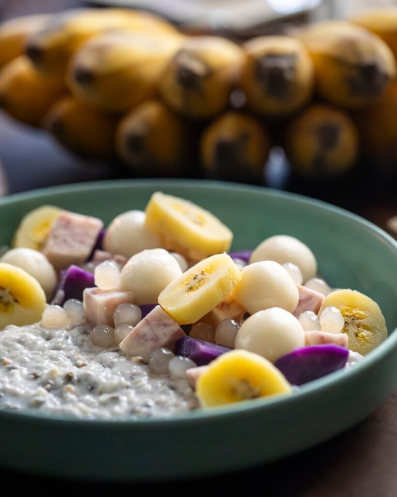 A close-up of Guinataang Munggo (Mung Bean Porridge) in a green bowl with bananas and jackfruit layered overtop.