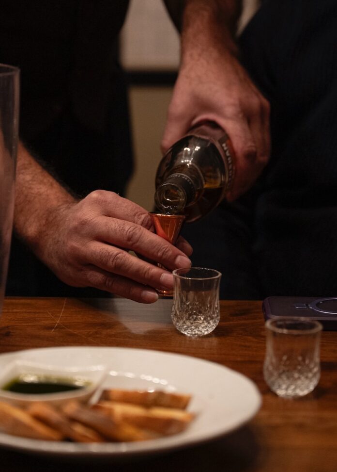 Gordon Valle pours Scotch from a bottle into a small tasting cup.
