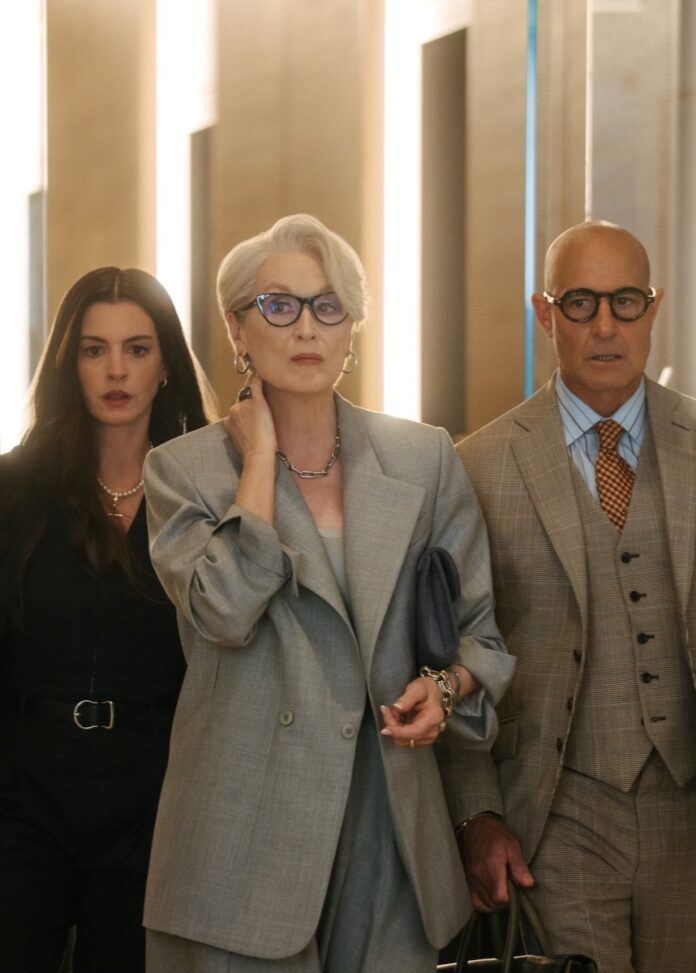 Anne Hathaway, Meryl Streep, and Stanley Tucci stand in a group during The Devil Wears Prada 2.