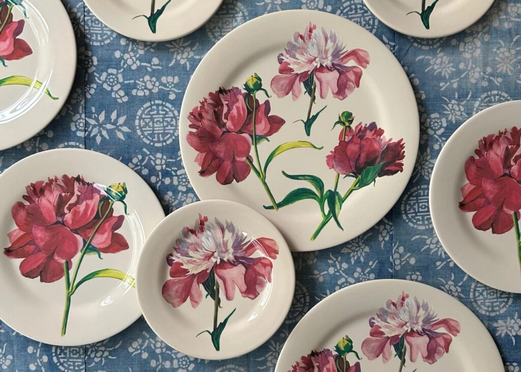 A set of white plates with hand painted peonies on them.