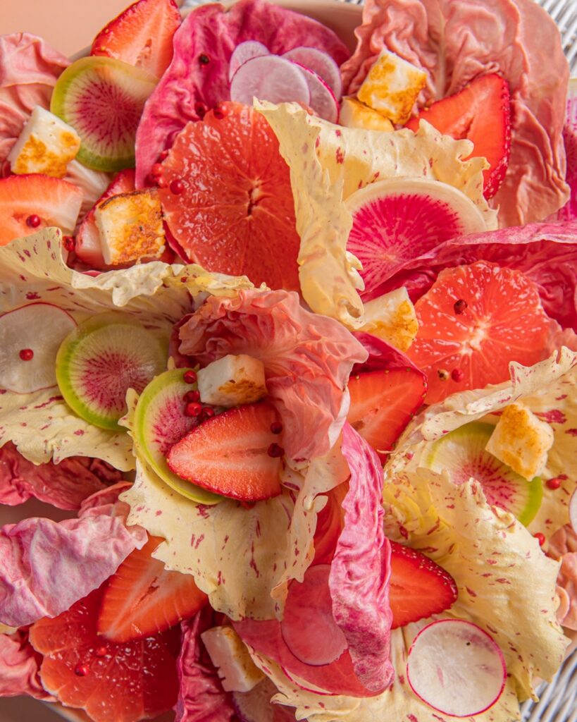 A close up of pink radicchio salad with strawberries and radishes.