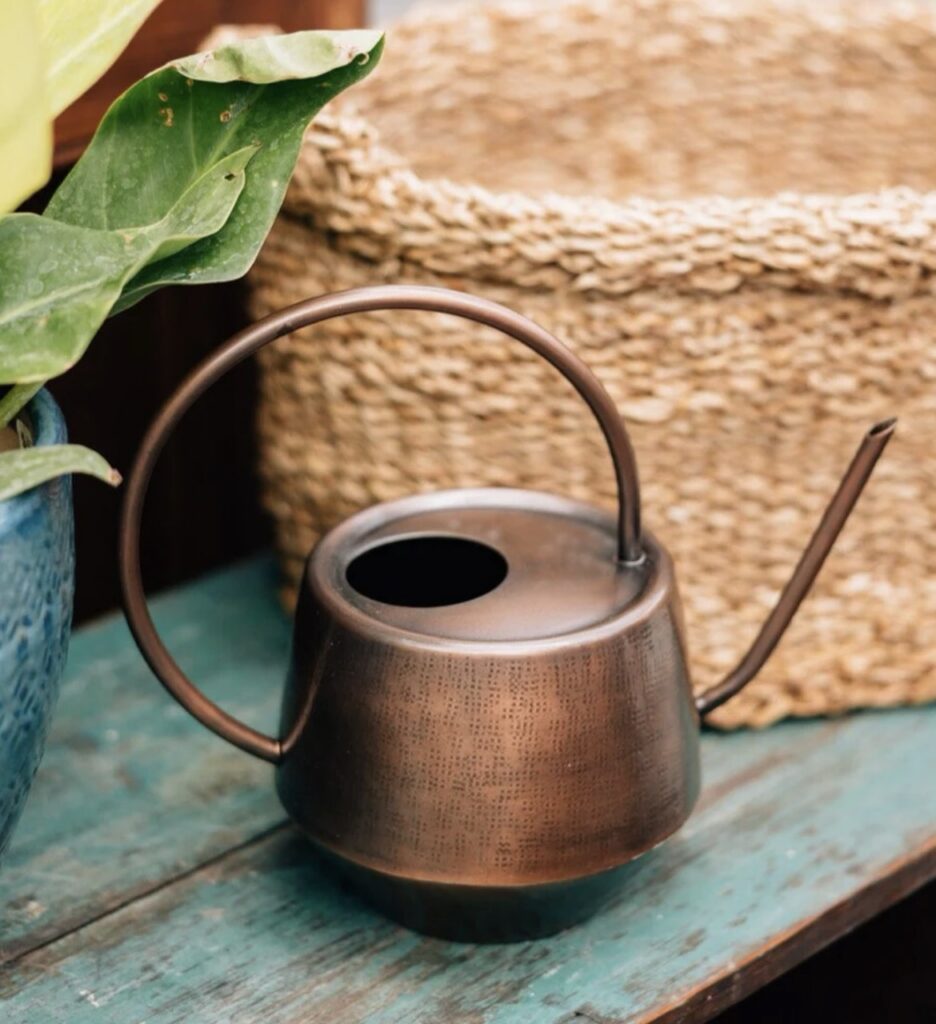 A copper watering can on a bench.