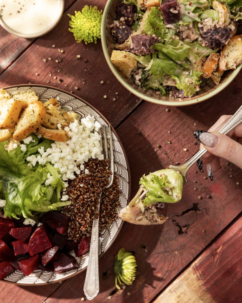 A person holds up a fork with greens from a grain bowl on it above the actual grain bowl.