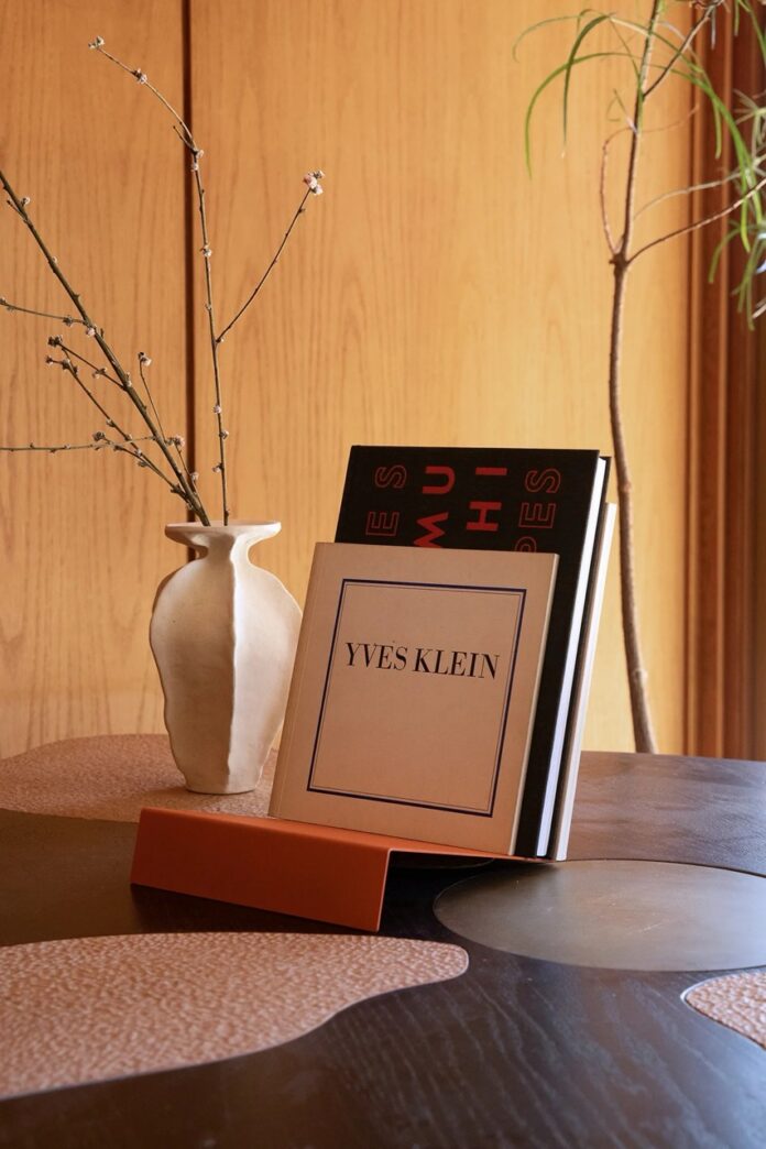A record stand holds an album beside a white vase.