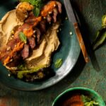 Sliced roasted lamb loin over chickpea purée drizzled with red green chile harissa and garnished with fresh mint.