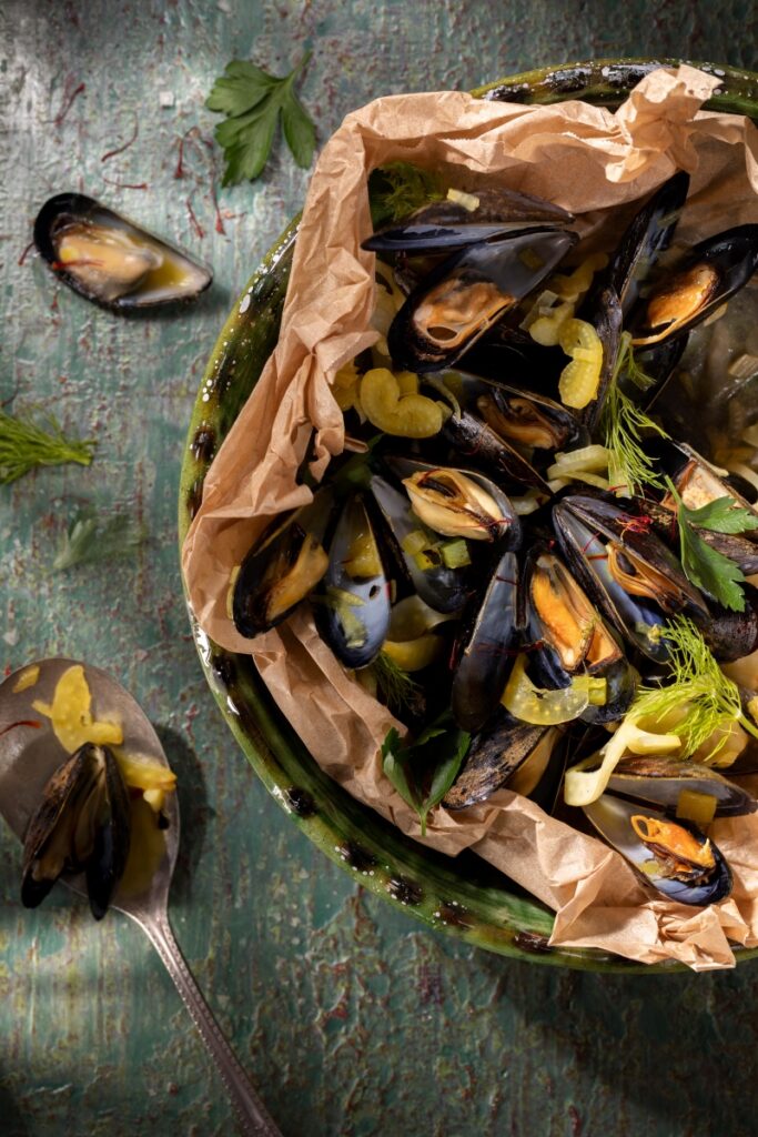 Mussels en papillote baked in parchment paper with green chile, saffron threads, and shaved fennel.