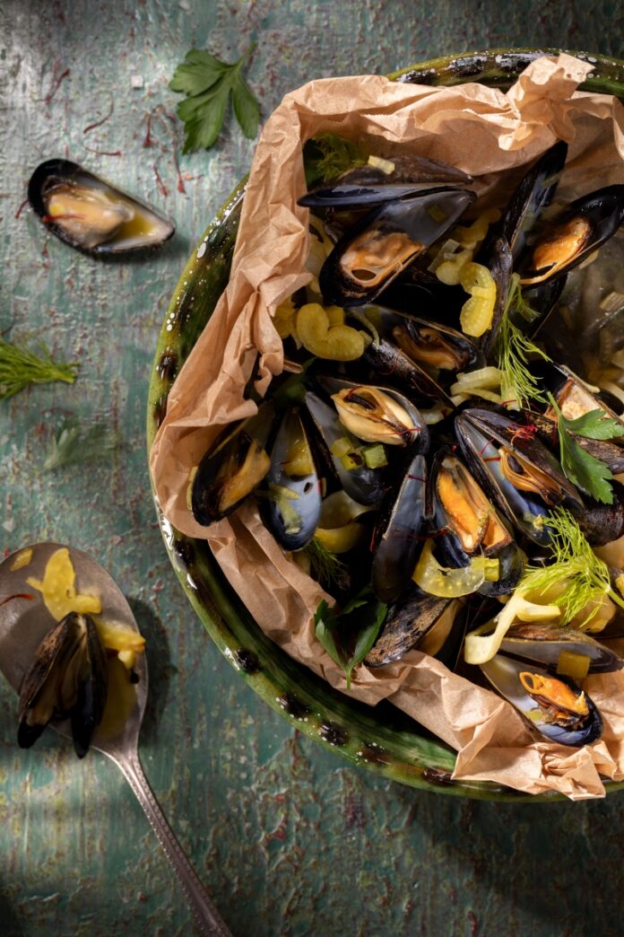 Mussels en papillote baked in parchment paper with green chile, saffron threads, and shaved fennel.