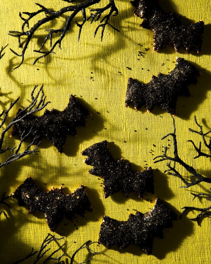 Batty Sweet Potato & Black Bean Hand Pies for Halloween TABLE Magazine Bat-shaped hand pies coated in black sesame seeds on a platter for a Halloween party.