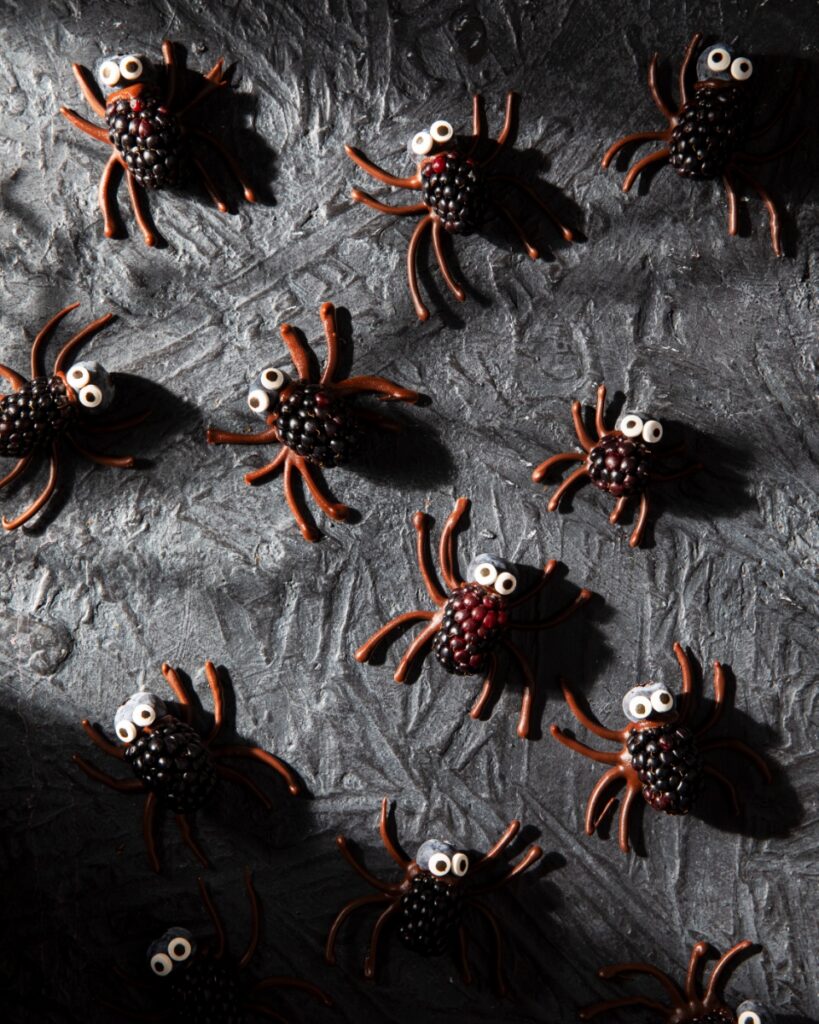 Berry Scary Spiders made from blackberries and blueberries with candy eyes and chocolate legs.