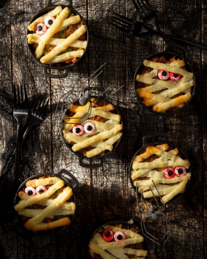 Mummified Shepherd’s Pie A Delicious Halloween Crowd-Pleaser TABLE Magazine Individual mini cast-iron crocks filled with Shepherd's pie and topped with piped mashed potato mummy wraps and candy eyeballs.