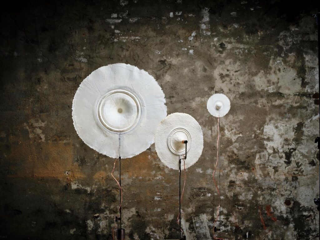 Three round white sound plates in varying sizes on stands by Studio Matthijs Koerts.