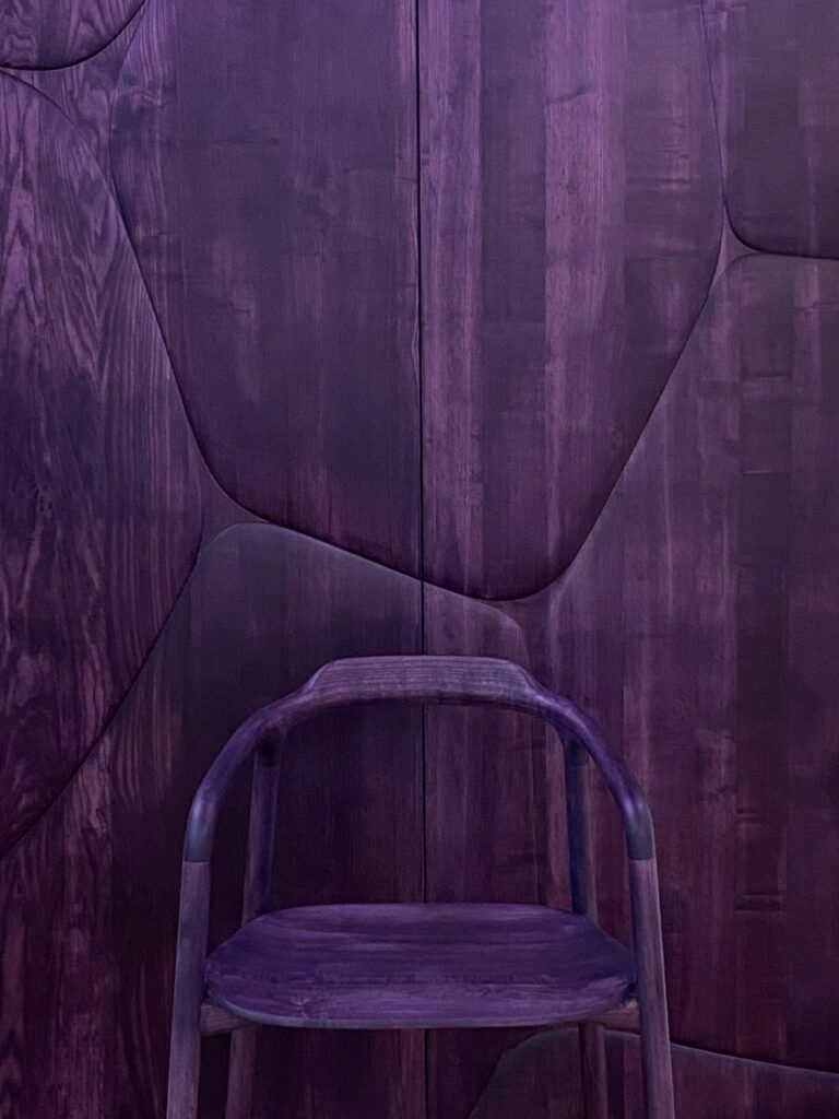 A purple chair by  Franck Genser against a purple stone wall.
